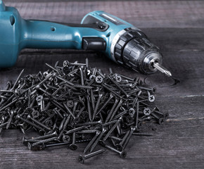 Pile of black screws and screwdriver  on wooden table