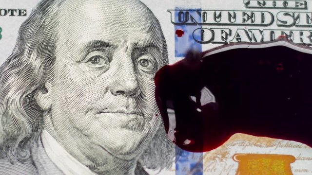 New Hundred Dollar bill with blood droplets hitting surface of Benjamin Franklin's face, taken at 600 frames per second.
