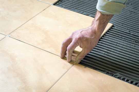 Builder puts the tiles on the floor, the repair