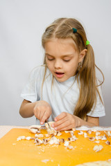 The little girl at the table with diligence knife cutting mushrooms