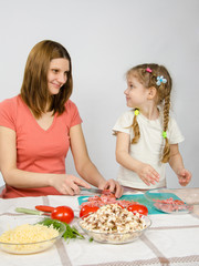 Obraz na płótnie Canvas Little six year old girl joyful enthusiasm helps mum to prepare food