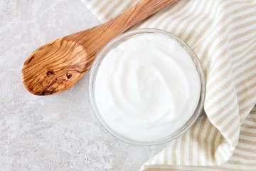 Foto op Plexiglas Greek yogurt in a bowl, downward view with cloth and spoon on a white marble © Jenifoto