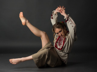 Beautiful happy cute young woman in Ukrainian embroidery dancing on a gray background