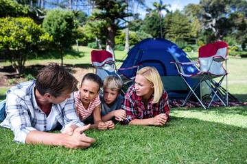 Fototapeta premium Family talking to each other while lying on grass