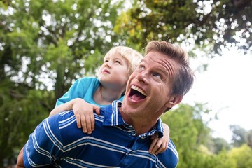 Naklejka premium Happy man giving piggyback to his son