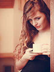 Woman drinking hot coffee beverage at home