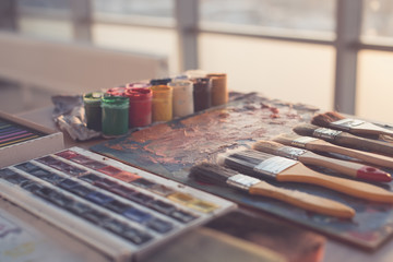 Photo of gouache and watercolor with brushes set in art studio. Oil paints smeared on palette