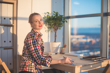 Fototapeta premium Side view of happy young woman working in home office, writing on paper. Female student learning material, doing task at workplace.