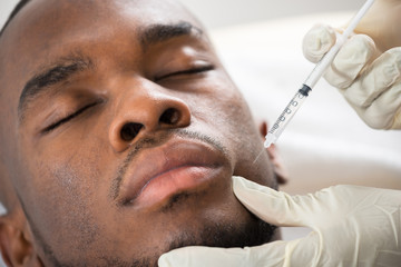 Person Hand Injecting Syringe On Young Man Face