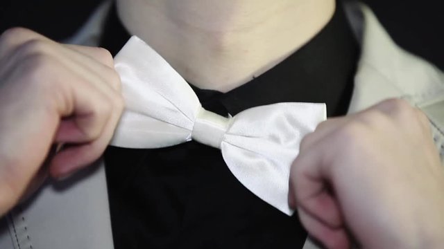 The man adjusts his bow tie