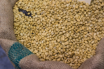 A coffee bean in a container with both roasted and raw. Represent a fresh and scent of coffee.