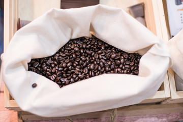 A coffee bean in a container with both roasted and raw. Represent a fresh and scent of coffee.
