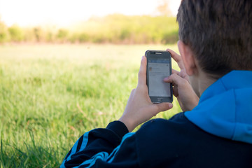 Teenager using a smart phone in beautiful field