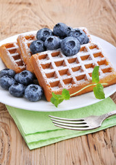 Sweet dessert: belgian waffles with blueberries sprinkled with powdered sugar.