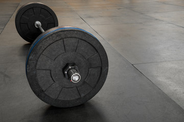 Obraz na płótnie Canvas Barbell with black and blue plates on a gym floor 