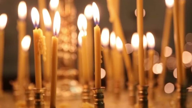 Candles burning in the darkness of the church. Flame on black background