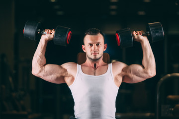 Naklejka na ściany i meble sport, bodybuilding, weightlifting, lifestyle and people concept - young man with dumbbells flexing muscles in gym