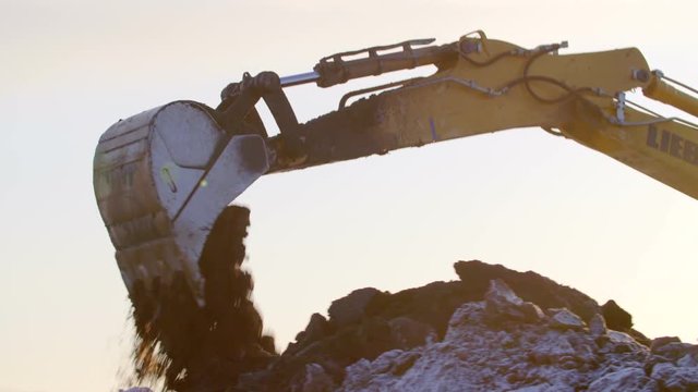 Excavator digging the ground in winter sunset