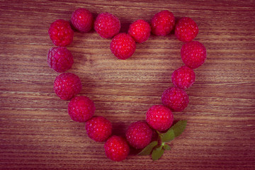 Vintage photo, Heart of fresh raspberries on wooden table, symbol of love