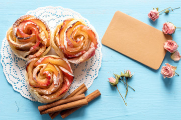 Homemade Apple rose cake with sugar powder on blue  wooden background.
Top view.  Handmade gift for mom/ Mothers day greeting card.
