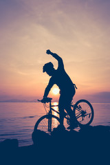Fototapeta na wymiar Healthy lifestyle. Silhouette of bicyclist riding the bike at seaside