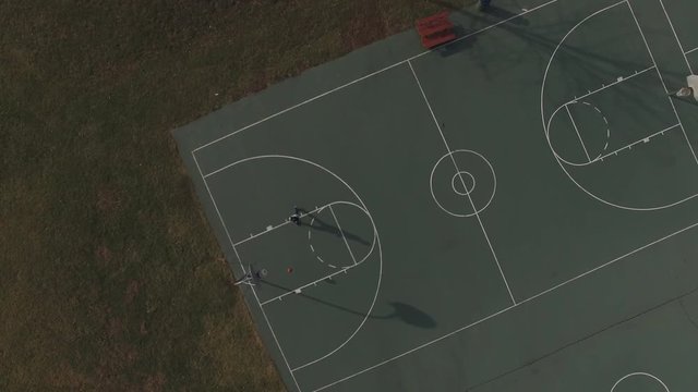 Kid playing basketball on court seen from overhead view.