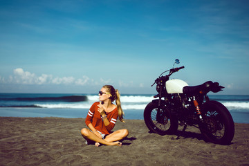 Naklejka na ściany i meble young pretty hipster girl Biker girl sitting on vintage custom motorcycle Biker girl sitting Outdoor lifestyle portrait. jeans short denim, fashion style