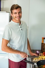 Portrait of man cutting vegetables in kitchen at home