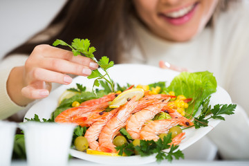 Positive girl arranging shrimps in plate