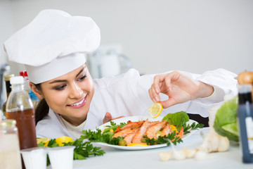 Female chef adding herbs to shrimps dish