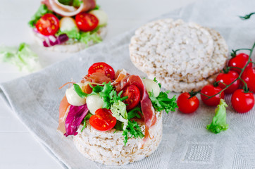 Sandwich with rice cake, lettuce, mozzarella, tomatoes and prosciutto