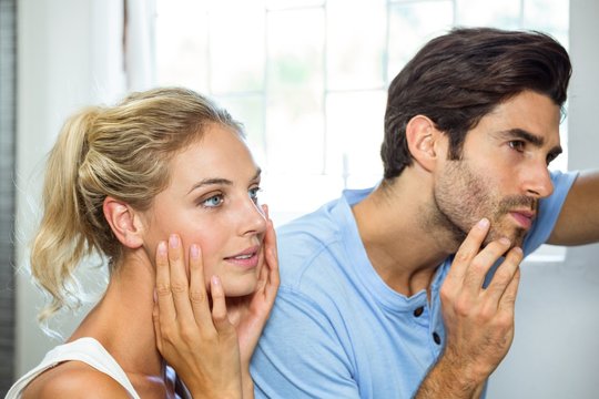 Man And Woman Checking Their Skin In Bathroom