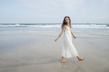 Woman wearing a white long dress is a walk in the seaside