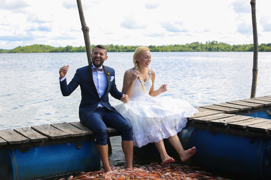 bride and groom sitting with their feet in water