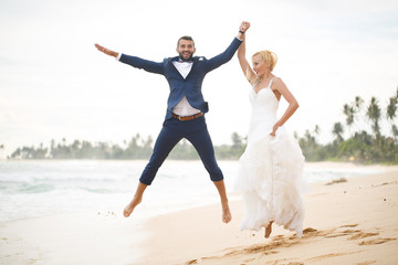 bride and groom playing on the beach