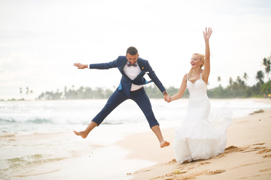 bride and groom playing on the beach