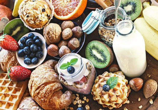 Health breakfast - with homemade granola, waffles, muffins,almond,hazelnuts,various fresh fruits, berries and milk on old wooden table. Health food concept .Top view.