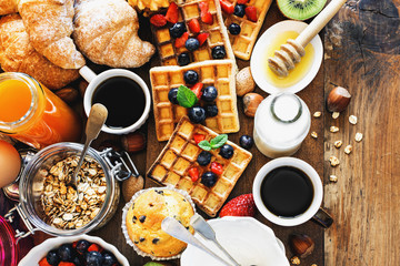Health breakfast - cup of coffee with homemade granola, waffles, muffins,almond,hazelnuts,various...