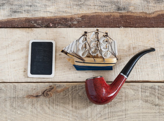 pipe and model classic boat on wood background