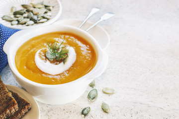 Curried carrot soup with cream and seeds on marble table. Selective focus.