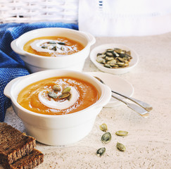 Curried carrot soup with cream and seeds on marble table. Selective focus.