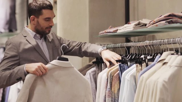 happy young man choosing clothes in clothing store