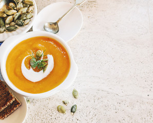 Curried carrot soup with cream and seeds on marble table. Selective focus.