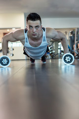 Man doing push up holding dumbbell at the gym