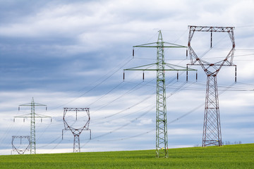 Pylons on green field under cloudy sky