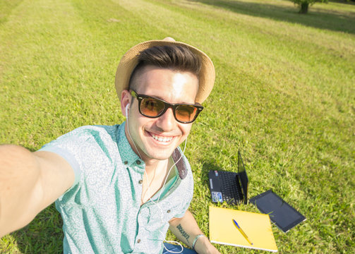 Attracive caucasian student take a selfie at the park using his smartphone
