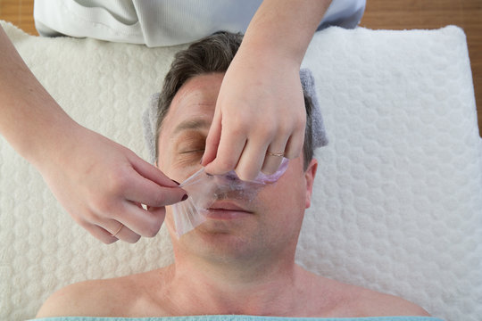 Therapist hands removing face mask to a man in Spa