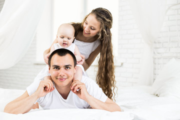 Fototapeta premium Mother and father with little baby in a bed