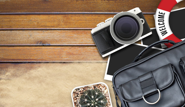 camera and blank photo frames on wooden table. top view, travel concept