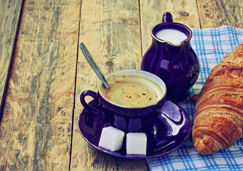 Blue coffee cup, milk jug and croissant